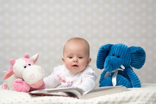 Baby girl reading a book with little friends