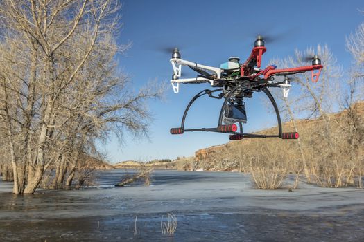 FORT COLLINS, CO, USA, March 9,  2015:  DJI F550 Flame Wheel  hexacopter drone is  flying with a camera over frozen lake.