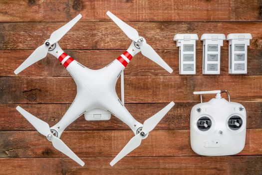 Fort Collins, CO, USA - March 17, 2015:  DJI Phantom 2 with a radio controller and spare LiPo batteries, top view against rustic wooden wood table