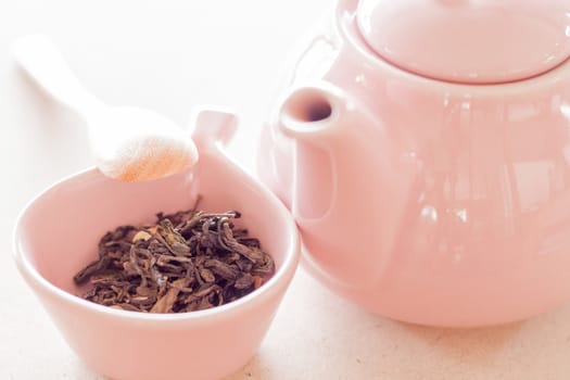 Oolong tea in ceramic cup, jar and wooden spoon, stock photo