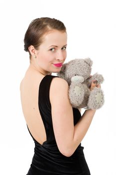attractive smiling brunette holding teddy bear in a black dress isolated on white