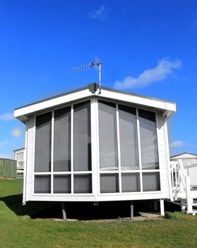 Exterior of a modern white caravan on a park in summer.