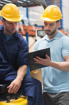 Focused warehouse workers talking together in warehouse