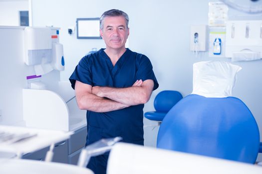 Dentist in blue scrubs smiling at camera at the dental clinic