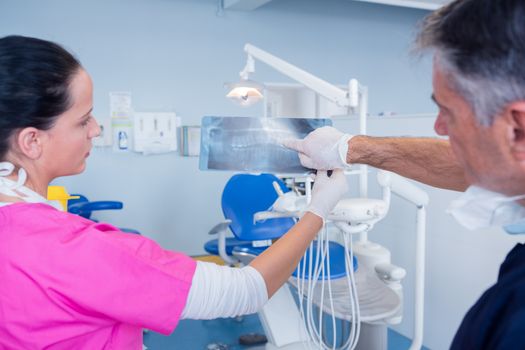 Dentist showing x-ray to his assistant at the dental clinic