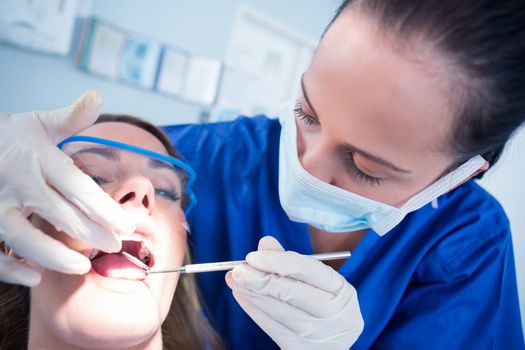 Dentist examining a patients teeth in the dentists chair at the dental clinic