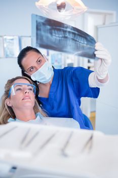 Dentist in mask explaining x-ray to patient at the dental clinic