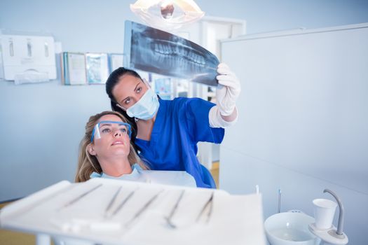 Dentist in mask explaining x-ray to patient at the dental clinic