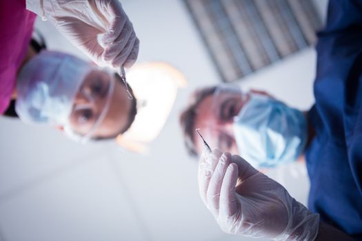 Dentist and assistant leaning over patient with tools at the dental clinic