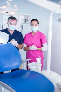 Dentist and assistant in surgical mask and protective glasses at the dental clinic