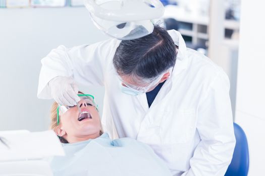 Dentist examining a patients teeth in the dentists chair at the dental clinic