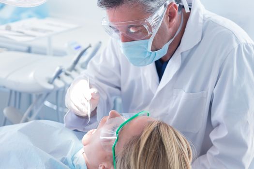 Dentist in surgical mask and gloves holding tool at the dental clinic