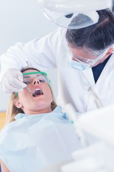 Dentist examining a patients teeth in the dentists chair at the dental clinic