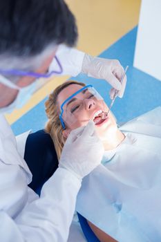 Dentist examining a patients teeth in the dentists chair at the dental clinic