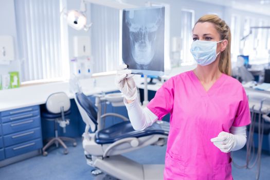Dentist in surgical mask looking an x-ray at the dental clinic