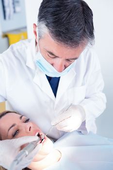 Dentist examining a patients with angled mirror at the dental clinic