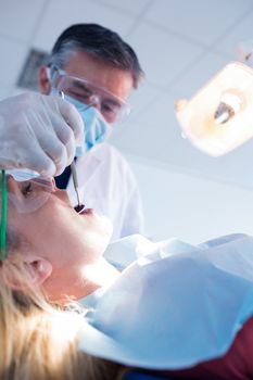 Dentist examining a patients teeth under bright light at the dental clinic