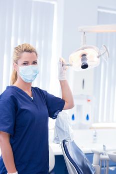 Dentist in mask holding light at the dental clinic