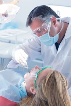 Dentist examining a patients teeth in the dentists chair at the dental clinic