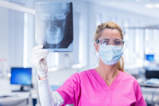 Dentist holding an x-ray and looking at camera at the dental clinic