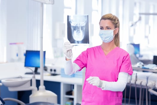 Dentist in surgical mask looking an x-ray at the dental clinic