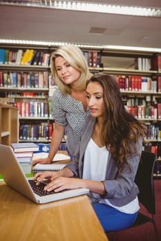 Blond mature student helping her classmate in library