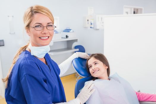 Smiling pediatric dentist with a happy young patient in dental clinic