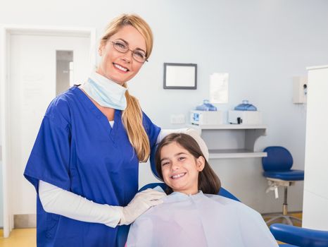 Smiling pediatric dentist with a happy young patient in dental clinic