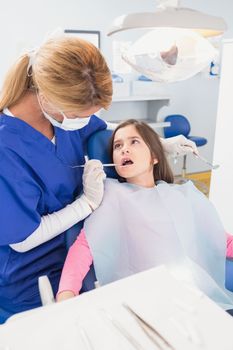 Pediatric dentist examining her young patient in dental clinic