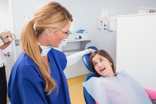 Smiling pediatric dentist with a happy young patient in dental clinic