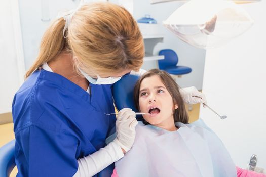 Pediatric dentist examining her young patient in dental clinic