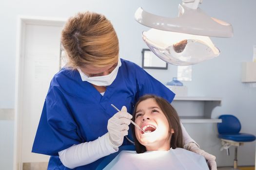 Pediatric dentist examining her young patient in dental clinic