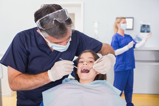 Pediatric dentist examining her young patient in dental clinic