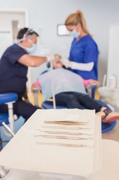 Dentist and his dental assistant examining a young patient in dental clinic