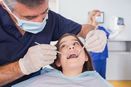 Pediatric dentist examining her young patient in dental clinic