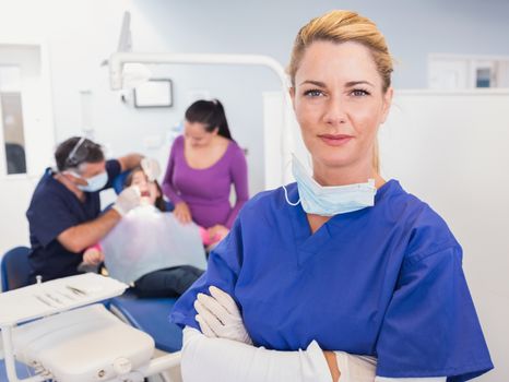 Dentist with folded arms with patient behind her