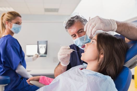 Pediatric dentist examining her young patient in dental clinic