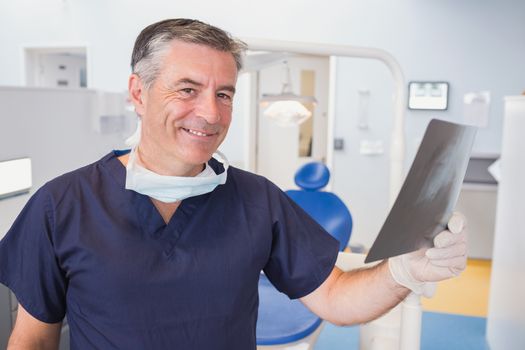Smiling dentist examining a x-ray in dental clinic
