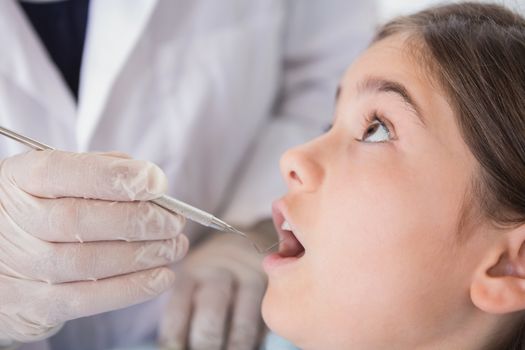 Pediatric dentist examining his nervous young patient in dental clinic
