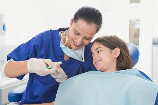 Pediatric dentist explaining to young patient how use toothbrush in dental clinic