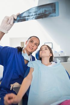 Pediatric dentist explaining to young patient the x-ray in dental clinic