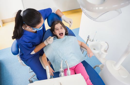 Pediatric dentist examining her patient with mouth open in dental clinic