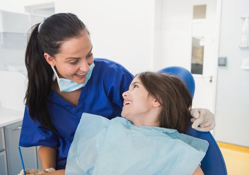 Cheerful pediatric dentist with a smiling young patient in dental clinic