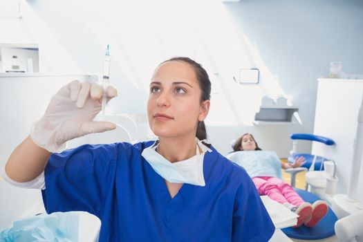 Pediatric dentist preparing an injection with terrified patient behind her