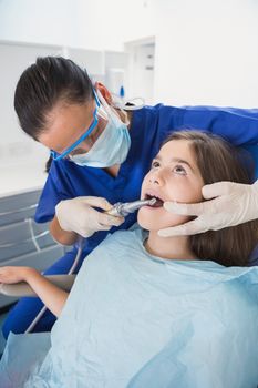 Pediatric dentist wearing safety glasses examining her young patient 