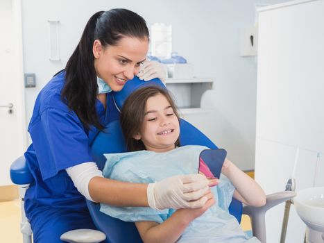 Pediatric dentist and young patient holding a mirror  in dental clinic