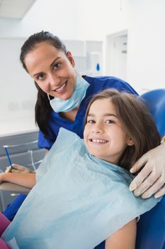 Smiling pediatric dentist with a cute young patient in dental clinic