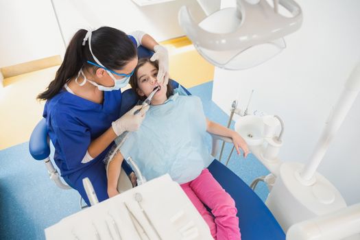 High angle view of pediatric dentist examining her young patient in dental clinic