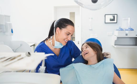 Cheerful pediatric dentist with a smiling young patient in dental clinic