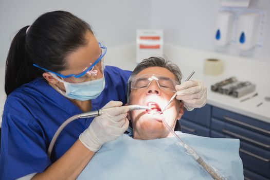 Dentist examining a patient with tools and light in dental clinic